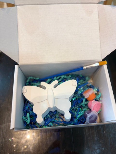 Butterfly figurine in a box with colorful materials and a paintbrush
